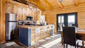 A modern kitchen with wooden walls, stainless steel appliances, and a central island with bar stools.