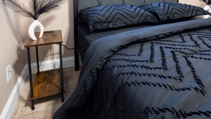 Un dormitori amb un llit, una tauleta de nit i un vas decoratiu.