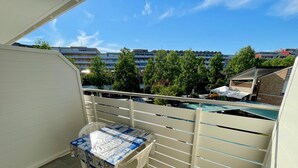 A balcony with a table and chairs, a view of buildings, and trees. - Cozy studio near the beach (Porto Santa Margherita)