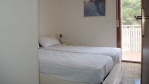 A bedroom with two beds, a painting on the wall, and a view of a balcony.