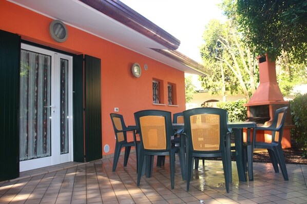 An outdoor patio with a table and chairs, a sliding glass door, and a red chimney.
