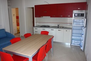 Une cuisine compacte comprenant une table et des chaises, un four à micro-ondes et un réfrigérateur.