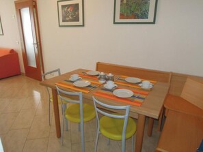 Un comedor con una mesa dispuesta para cuatro personas, sillas y un banco rojo.