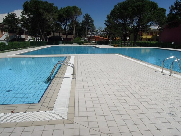 Piscina com revestimento de azulejos e corrimãos de metal.