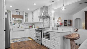 Una cocina moderna con armarios blancos, electrodomésticos de acero inoxidable y una isla central.
