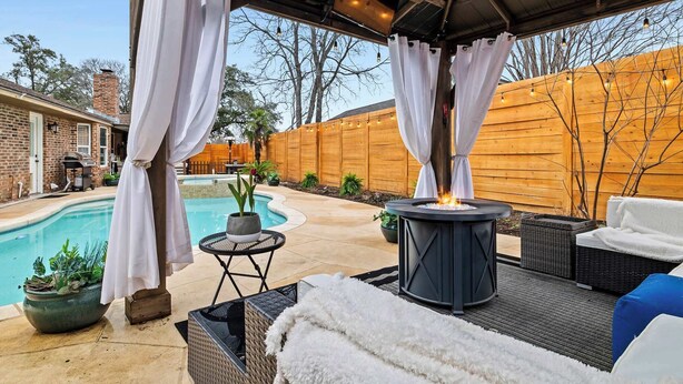 Un patio techado al aire libre con piscina, zona de estar y un hogar para fuego.