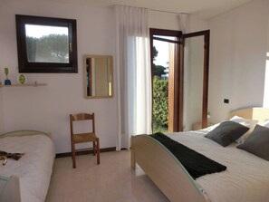 Une chambre avec deux lits, une chaise, une fenêtre et un miroir.
