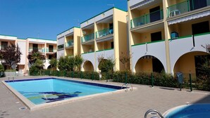 Una piscina rodeada de edificios de varios pisos con balcones y un cielo despejado.