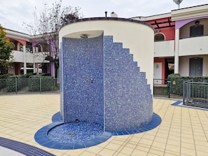 Una vasca d'acqua circolare con decorazioni in mosaico, circondata da un percorso piastrellato.