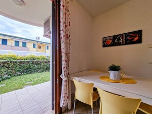 Une pièce comprenant une table à manger, des chaises jaunes, une plante en pot et un tableau accroché au mur.