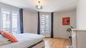 Un dormitorio con una cama, una ventana con cortinas, una obra de arte colgada en la pared y una chimenea.