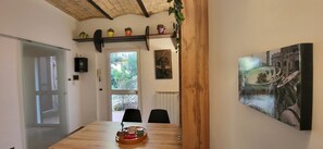 A dining area with a wooden table, chairs, a tray with items, a door, a window, and a wall with a framed picture. - La Casetta con giardino al Pigneto (Rome)