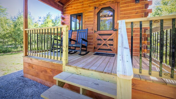 A wooden cabin with a porch, rocking chairs, and a bench. - The Birch – New!  Menominee River Boutique Cottage (Porterfield)
