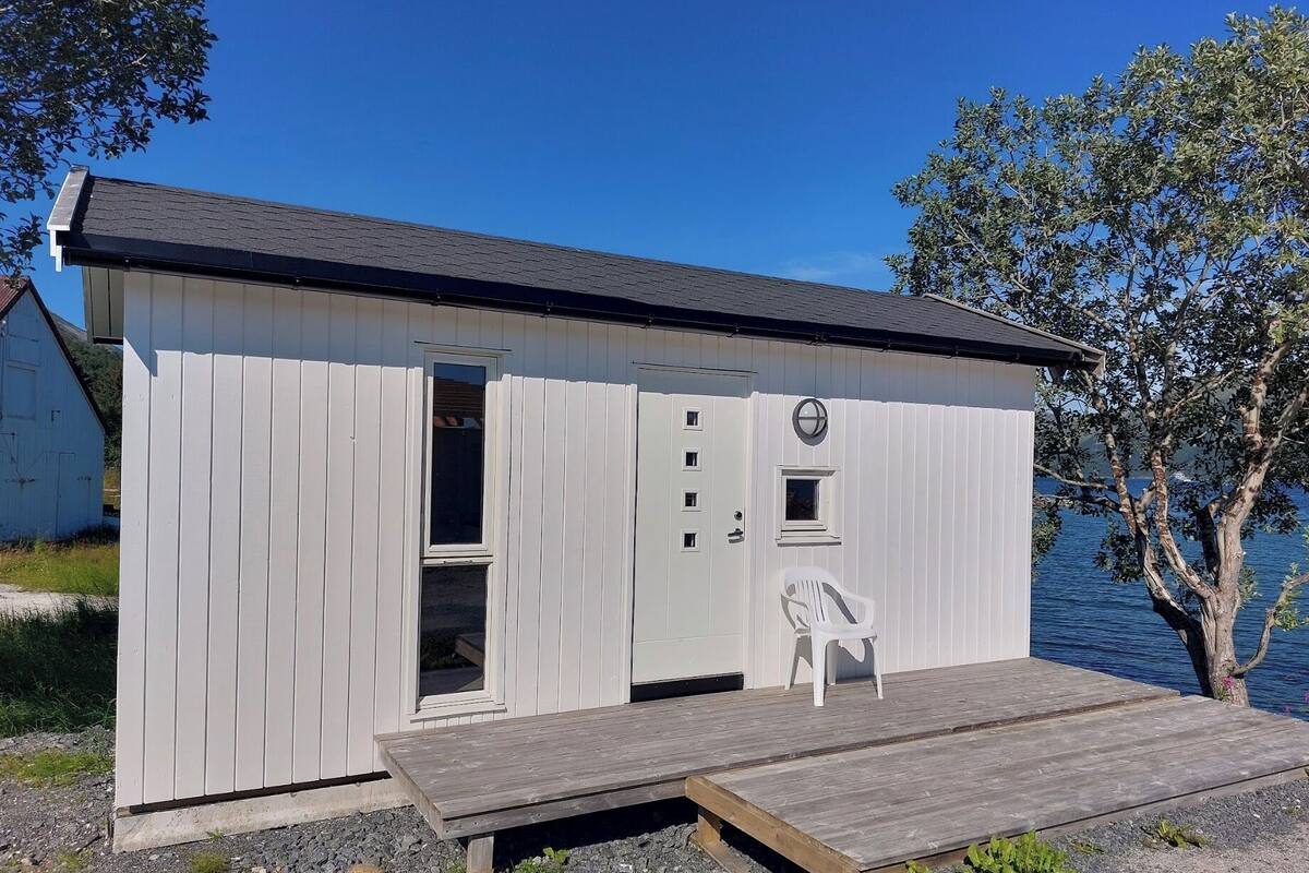 A small, single-story cabin with a dock, a small window, and a door.