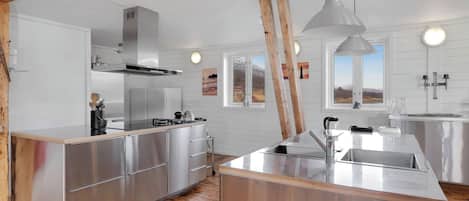 A modern kitchen with stainless steel appliances, wooden beams, and a large island.