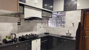 Una cocina moderna con armarios blancos y negros, una estufa a gas y una ventana con rejas.