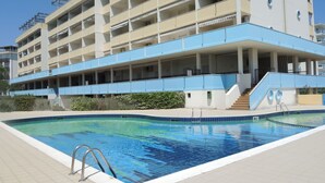 A modern hotel with a swimming pool, multiple balconies, and a covered outdoor area. - Lovely flat with shared pool - Beahost (Bibione)