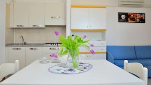 A modern kitchen with white cabinets, a gas stove, and a dining area with a table set for two.