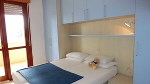 A bedroom with a bed, a nightstand, a teddy bear, and a window with blinds.