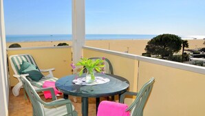 Un balcon avec une table et des chaises, donnant sur une plage.