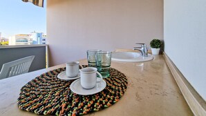 A balcony with a table set for two, a sink, and a small potted plant. - Luminous one bedroom flat with side sea view (Bibione)