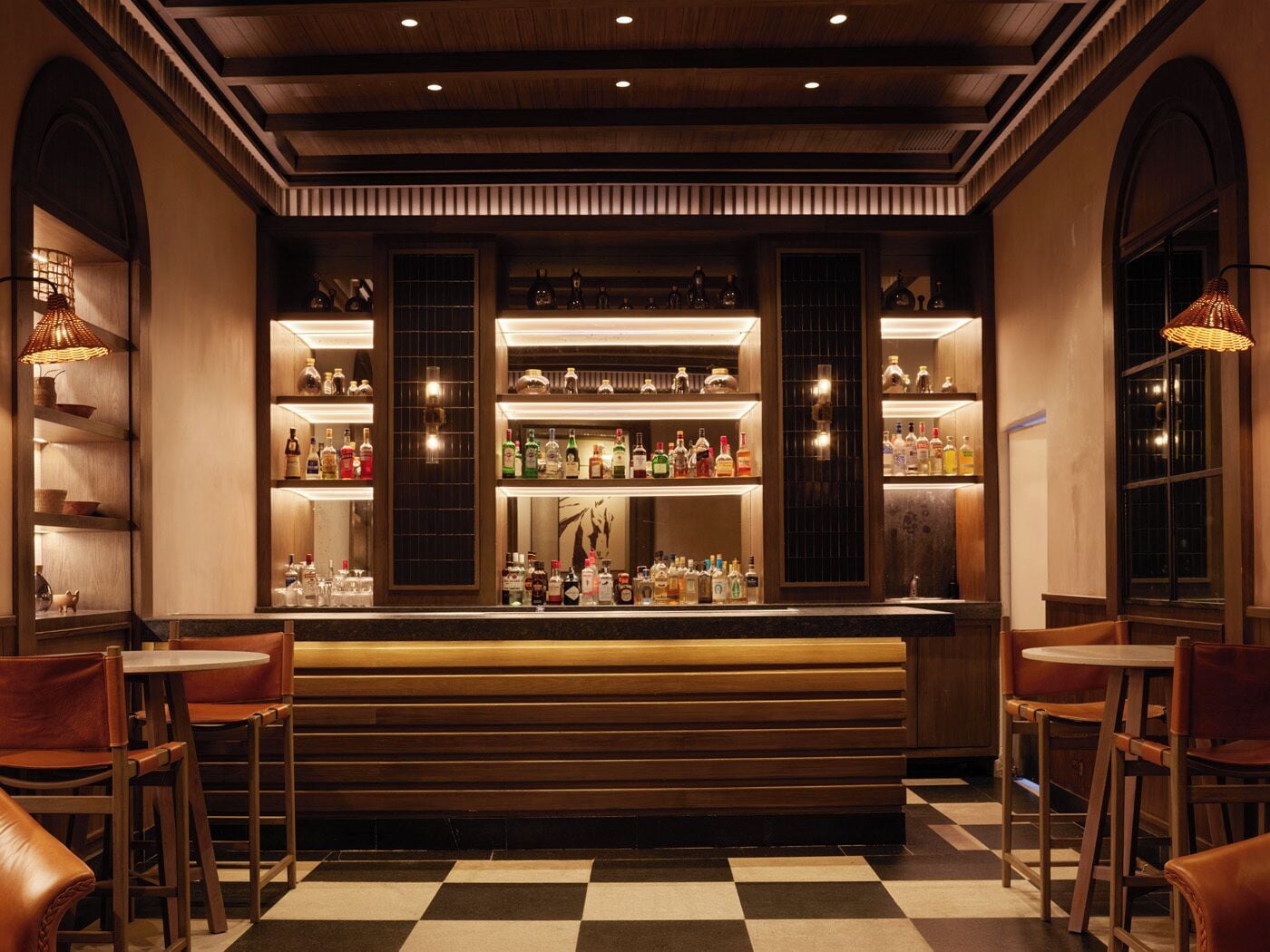 Zona de bar con piso a cuadros, mostrador de madera y asientos.