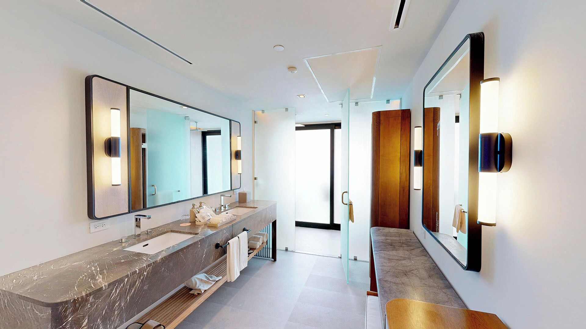 Un baño moderno con un espejo grande, dos lavamanos y un mueble de tocador.