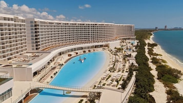 Un hotel grande con múltiples balcones, una piscina central y ubicación frente a la playa.