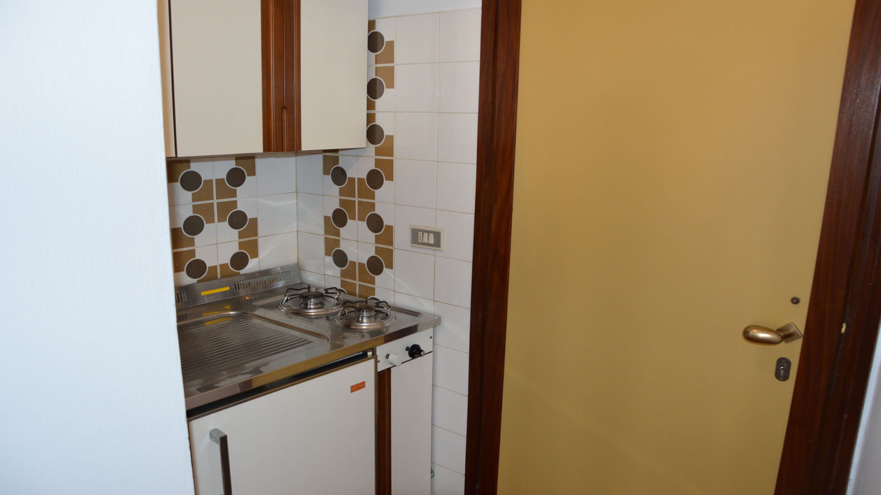 A compact kitchen with a stove, sink, and tiled backsplash.