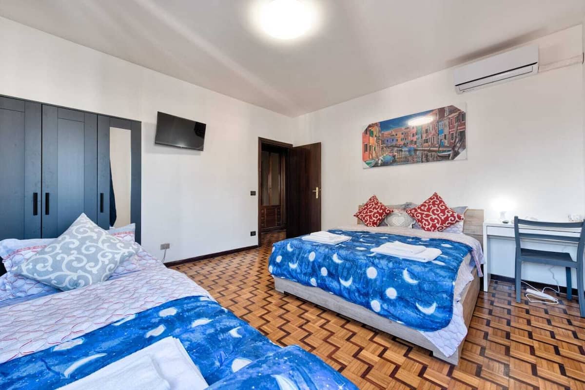 Ein Hotelzimmer mit zwei Betten, einem Schreibtisch und einem Bild an der Wand.