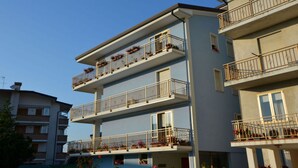 A multi-story residential building with balconies, windows, and a clear sky. - Spacious apartment close to the beach (Caorle)