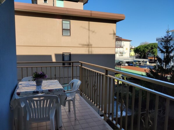 A balcony with a table and chairs, a potted plant, and a view of the cityscape.