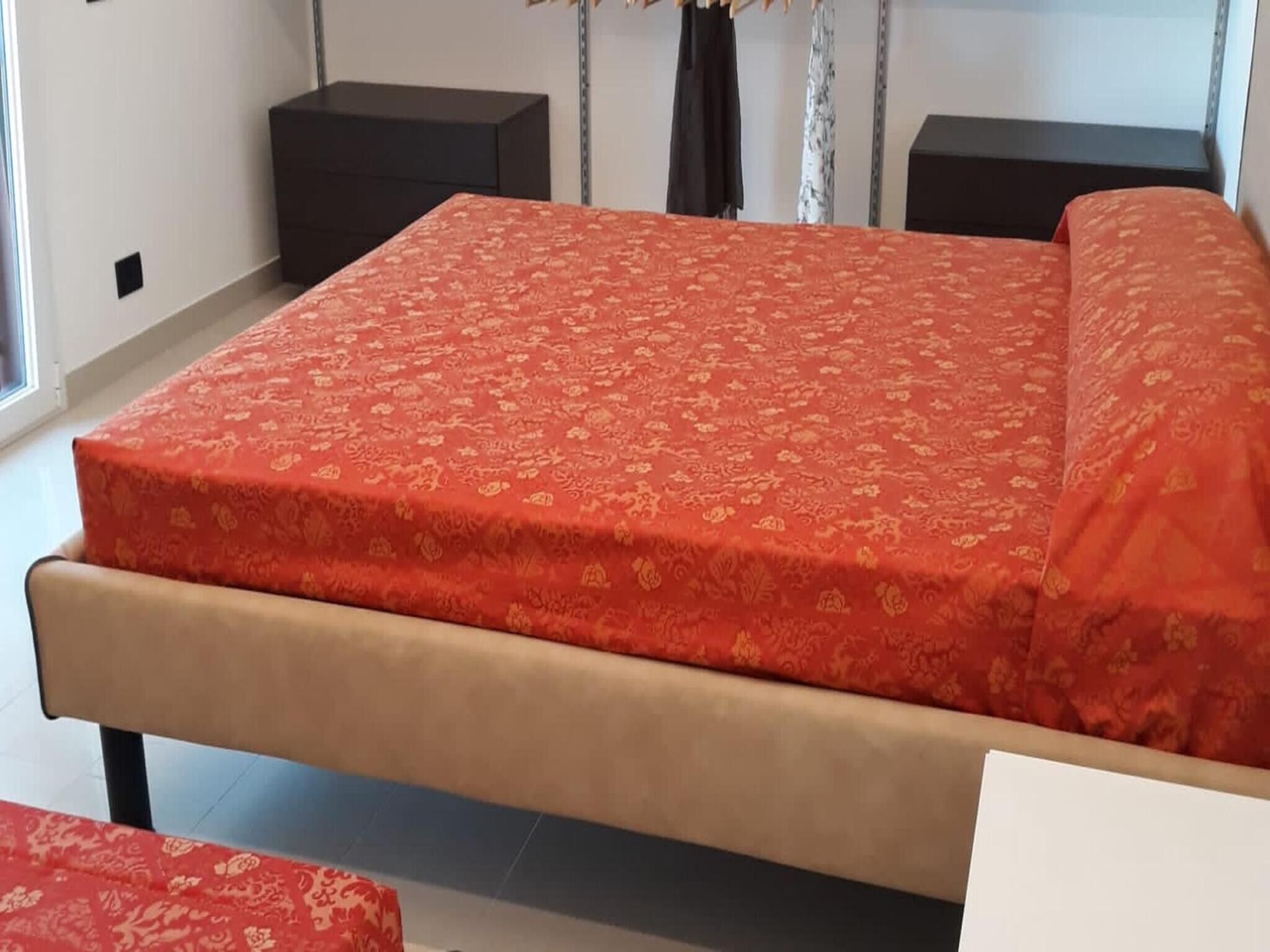 A bed with a patterned bedspread, a headboard, and a nightstand with a lamp.