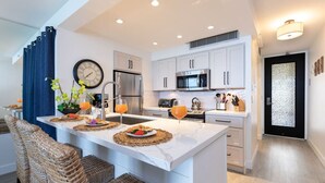 A modern kitchen with white cabinets, stainless steel appliances, and a central island with seating. - ❤️Best Views on Maui! Perfect for Honeymooners!!❤️ (Lahaina)