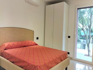 Ein Schlafzimmer mit einem Bett, einem Kleiderschrank und einer Schiebetür zu einem Außenbereich.