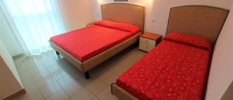 Habitación de hotel con dos camas, una mesita de noche, una pequeña mesa y un cuadro en la pared.