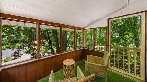 A sunroom with large windows, a small round table, and wicker chairs.