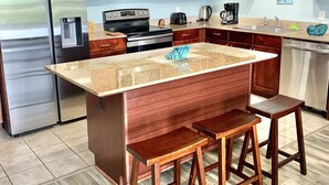 A modern kitchen with wooden cabinets, stainless steel appliances, and a granite countertop. - PCB SNOWBIRDS PARADISE/GOLF/5POOLS/SOME HEATED/STEPS TO BEACH (Panama City Beach)