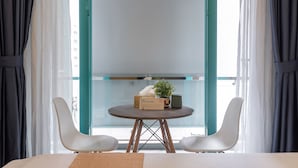 Quarto moderno com uma mesa redonda, duas cadeiras brancas, um vaso de planta e um aviso indicando área para fumantes.