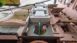 Um edifício de vários andares com um átrio central, diversas varandas e uma unidade de ar condicionado visível.