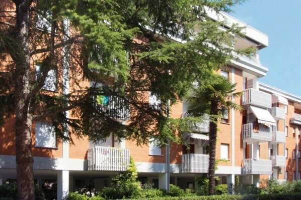 A multi-story hotel with balconies, a brick facade, and surrounding greenery.