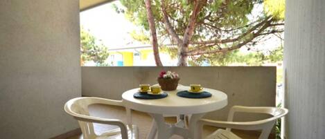 Un pequeño patio al aire libre con una mesa redonda y dos sillas.