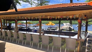 An outdoor bar area with a view of boats on the water, covered by a wooden canopy with colorful decorations. - Pocono Retreat -1 Mile to Lake and Skiing (Lake Harmony)