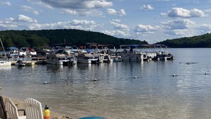 A marina with boats docked, a sandy beach with chairs, and a forested hill in the background. - Pocono Retreat -1 Mile to Lake and Skiing (Lake Harmony)