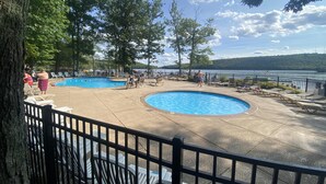 A pool area with two swimming pools, surrounded by lounge chairs and a view of a lake. - Pocono Retreat -1 Mile to Lake and Skiing (Lake Harmony)
