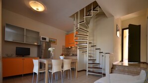 A compact living space with a kitchen, dining area, and a staircase leading to an upper level. - Spacious and bright apartment (Bibione)