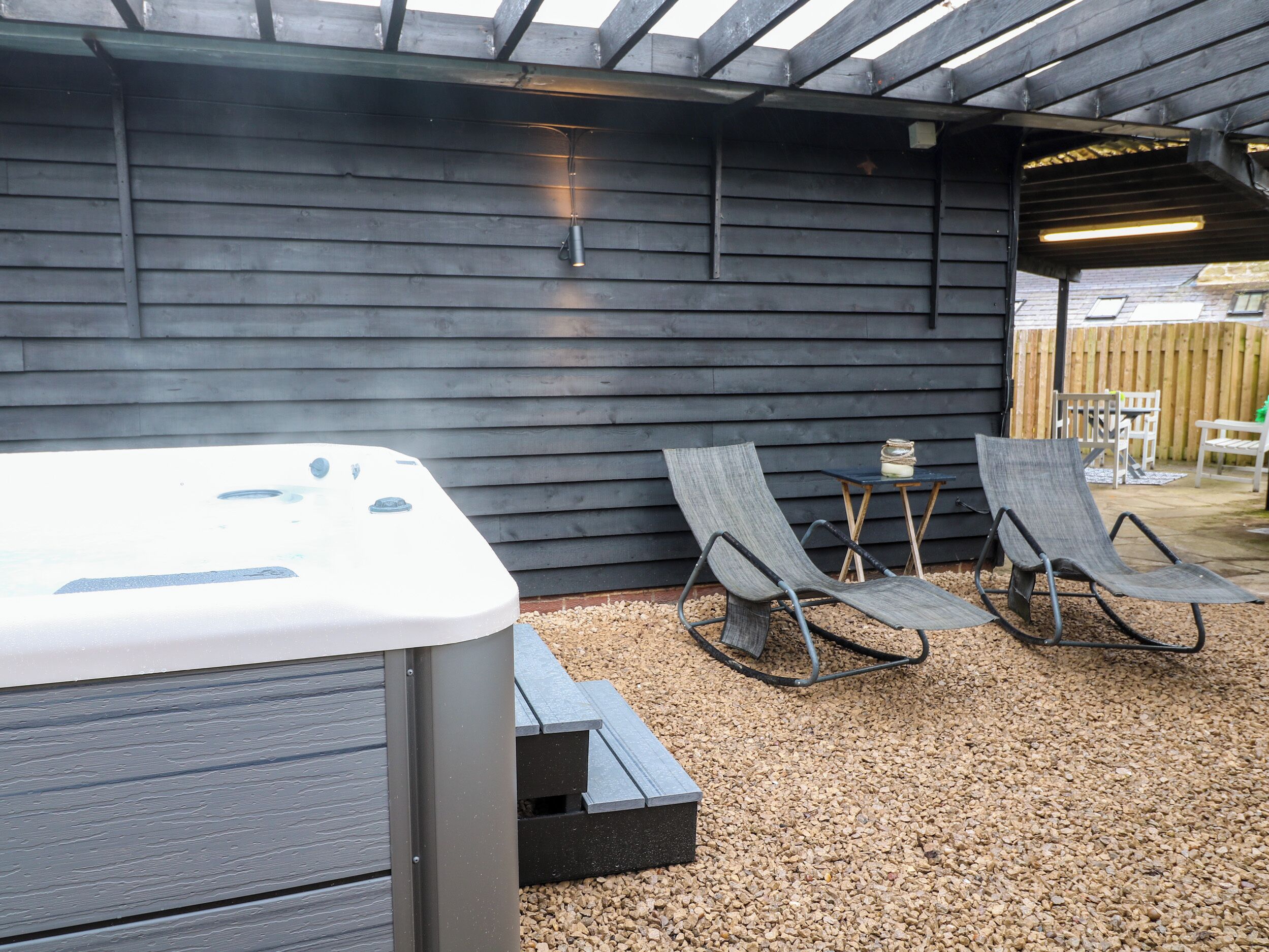 Un área de estar al aire libre con dos sillones y un jacuzzi.