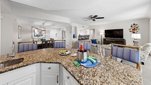 A modern kitchen with granite countertops, a built-in oven, and a dining area with a table and chairs. - Gullwing Resort 1002- A beachfront condo with amazing beach and bay views (Fort MyersBeach)