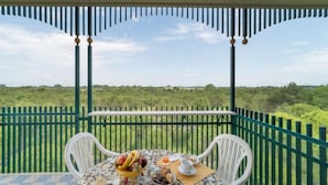 Un balcón con una mesa lista para el desayuno, con vistas a un paisaje verde y exuberante.