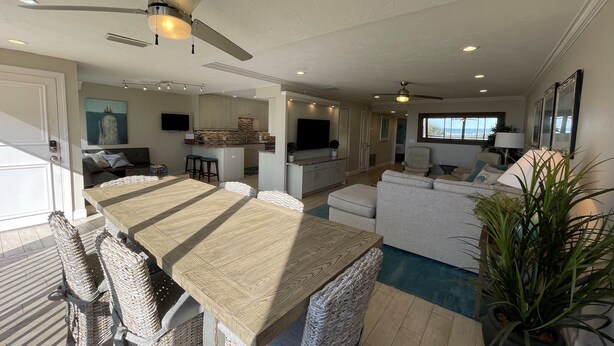 A spacious living area with a dining table, wicker chairs, a sofa, and a ceiling fan. - Exquisite Deluxe beachfront condo (Sarasota)